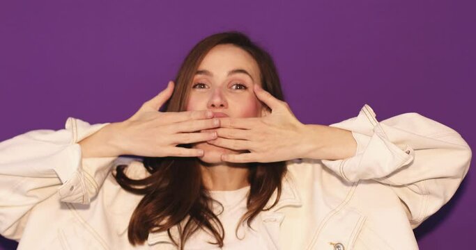 Amazed excited woman hairstyle in white jeans jacket open face in surprise looking at camera with big eyes, shocked, cover mouth. Indoor studio shot isolated on purple background. Oh my god wow!