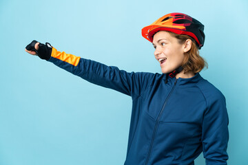 Young cyclist woman isolated on blue background giving a thumbs up gesture