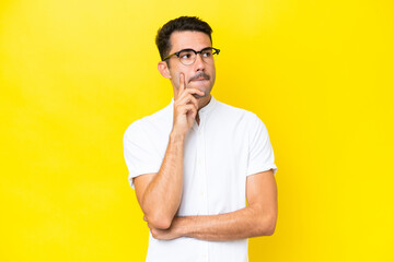 Young handsome man over isolated yellow background having doubts and thinking