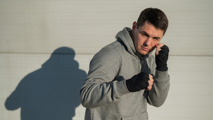 Close-up portrait of a man in kickboxing training against a gray wall. 