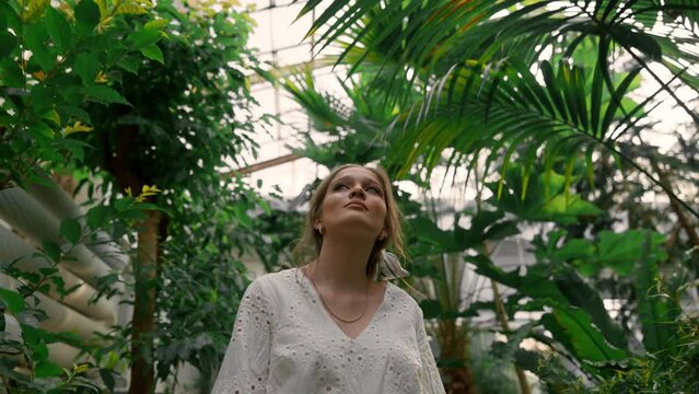 Portrait of pretty young woman watching big leafs plants in tropical botanic garden