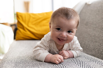 Happy smiling baby boy lying on sofa and looking at camera