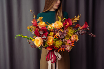 Woman holding orange Autumn Colorful fall bouquet. blooming flowers festive background, autumn orange and red flowers. bouquet floral card. Mothers day, International Women's Day.