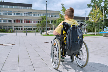 Back view, child preteen boy on wheelchair going to school building