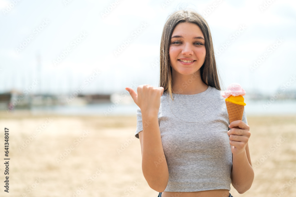 Poster Teenager girl with a cornet ice cream at outdoors pointing to the side to present a product