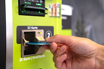 close-up of male hand hold credit card, young man using device bank terminal for cash dispensing,...