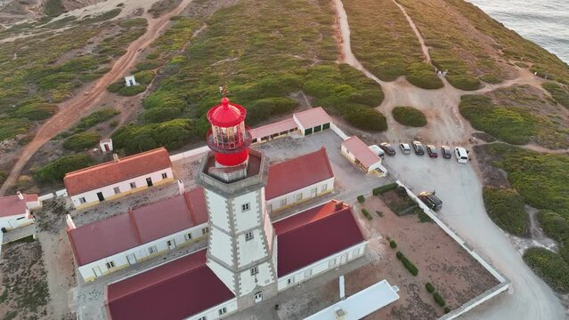 Aerial drone view of lighthouse on Cabo Espichel cape Espichel on Atlantic ocean at sunset. Sesimbra, Portugal. Tilt shot