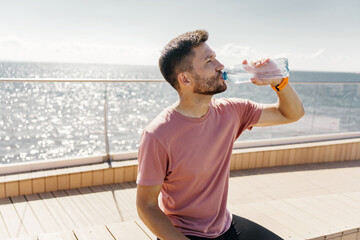 Drinks water from a bottle, rest break. Athlete runner training in sportswear.   A sporty man...