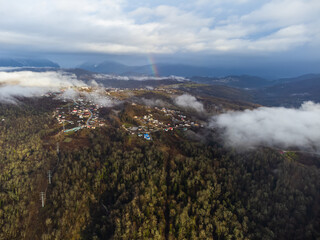 Drone shot through clouds of long mountain village on mountain ridge in rural jungle bush forest. High quality photo