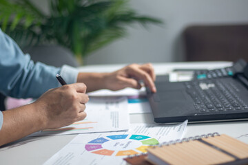 The astute business analyst is meticulously dissecting revenue graphs on the workstation, while...