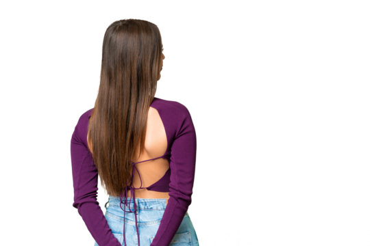 Young beautiful woman over isolated chroma key background in back position and looking back