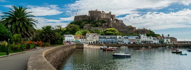 Poster Panoramic image of Mont Orgueil Castle in Gorey on the island of Jersey in the Channel Islands. Fishing boats and colourful buildings with sunshine and blue sky © Scott