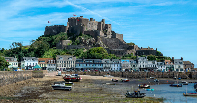Landscape image of Mont Orgueil Castle in Gorey on the island of Jersey in the Channel Islands. Fishing boats and colourful buildings with sunshine and blue sky