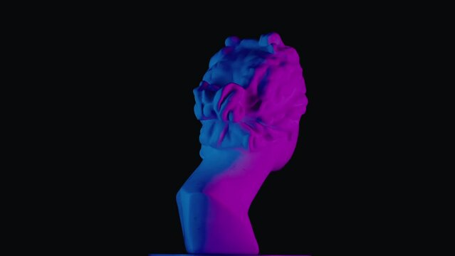 Closeup shot. Ancient marble bust statue of roman era woman in neon light spinning round on a platform. Isolated on black background.