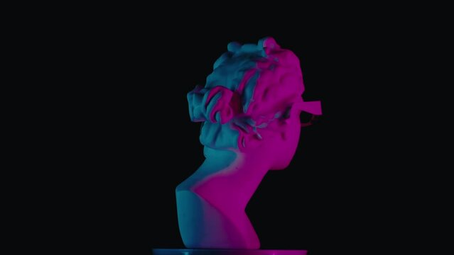 Closeup shot. Ancient marble bust statue of roman era woman in 3d glasses spinning round on a platform in neon lights. Isolated on black background.
