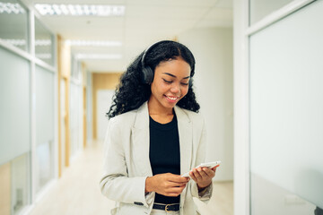 Shot of elegant young business woman smiling and  using mobile phone while walking, Copy space.