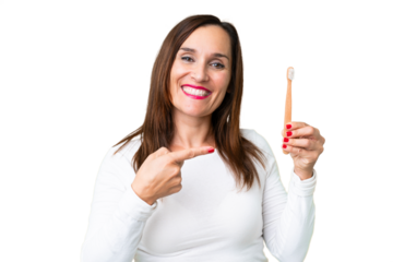 Middle age woman brushing teeth over isolated chroma key background and pointing it