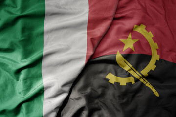 big waving national colorful flag of italy and national flag of angola .