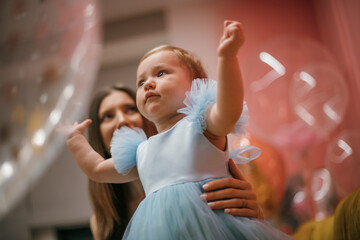 Family portrait. A little one-year-old girl in a princess dress with a young mother is happy and smiling.