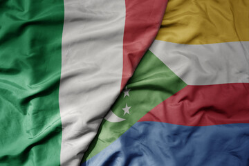 big waving national colorful flag of italy and national flag of comoros .