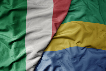 big waving national colorful flag of italy and national flag of gabon .
