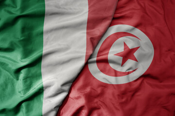 big waving national colorful flag of italy and national flag of tunisia .