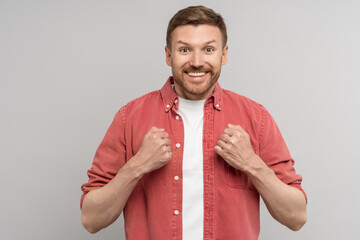 Excited smiling man rejoicing unexpected result holding fists. Handsome overjoyed male looks at...