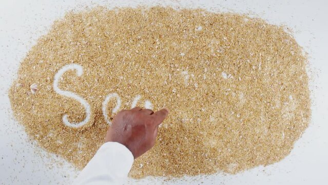 An Indian man's Hand Writes On Beach Sand words Sea food