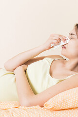 Fototapeta premium Portrait of young unhappy pregnant woman leaning on pillows on bed and blowing her nose into tissue. Future mom caught cold and sneezing