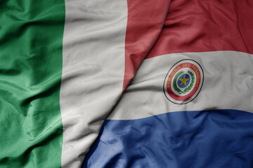 big waving national colorful flag of italy and national flag of paraguay .