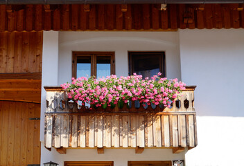 Fototapeta na wymiar idyllic scene with a traditional Bavarian rustic alpine farmhouse with pink geraniums on the balcony ledge in Schwangau in the Bavarian Alps on a summer day (Bavaria, Germany)