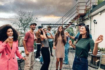 diverse happy young people dancing at rooftop party