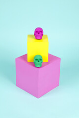 brightly colored plastic skulls on pink and yellow cubes