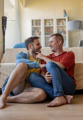 gay men couple at home sofa sitting showing affection