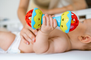 baby holds, plays with a rattle. A toy for the development of fine motor skills ,visual, auditory...