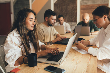 Coworkers sitting in a modern office, working using their laptops.