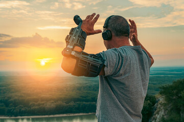 Man with adjustable articulated elbow orthosis on top cliff at sunset