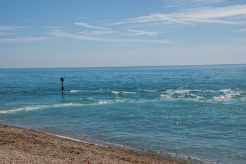Fototapeta na wymiar seaside sentry a coastal navigation marker in the sea at Selsey West Sussex England with blue sky in the background