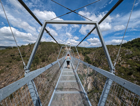 Estrutura metálica da ponte suspensa sobre o rio Paiva com alguns turistas ao fundo em Arouca, Portugal 