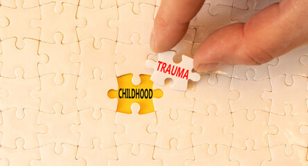 Childhood trauma symbol. Concept words Childhood trauma on beautiful white puzzles. Beautiful yellow paper background. Psychologist hand. Business psychology childhood trauma concept. Copy space.