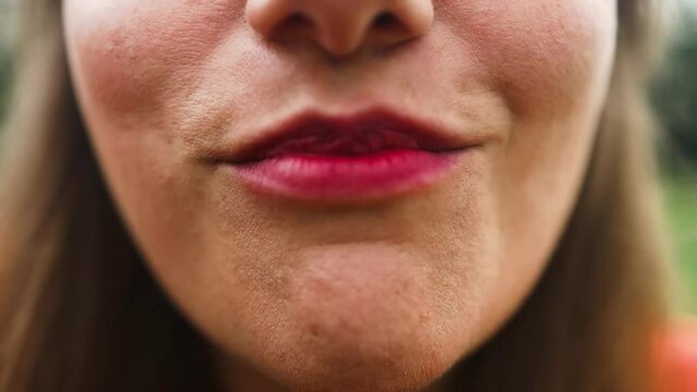 Perfect red female lips. Close up of pink female lips with raspberry. Beautiful female model lips eating raspberry. Pink lips with raspberry outdoors. High quality FullHD footage