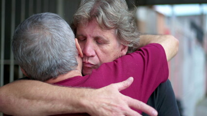 Heart-warming embrace between two senior friends in authentic loving hug. Two elderly people saying...