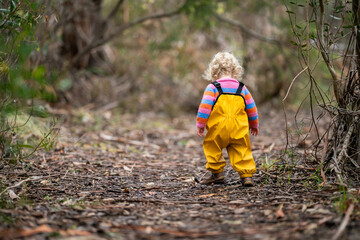 baby walking in a park in yellow overalls