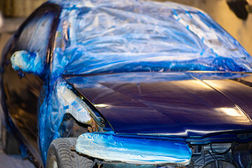 painting car body blue in car paint garage with colorful gun