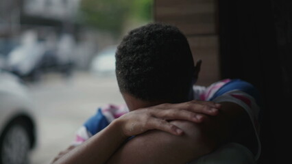 One depressed young black man struggles with social isolation and mental illness, covering face in...