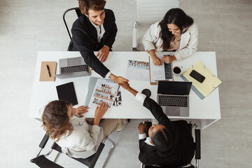 Top view of diverse businesspeople shaking hands after sealing a deal, concluding business agreement