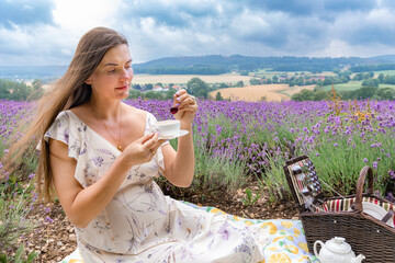 Young beautiful girl in white dress at picnic in the lavender field