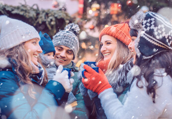 Group of friends drinking mulled wine in the cold on a Christmas Market with fun and laughter