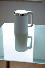 White electric kettle stands on a glass table