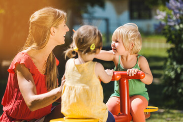 Children and nursery school teacher playing outdoors on a roundabout - 641402681
